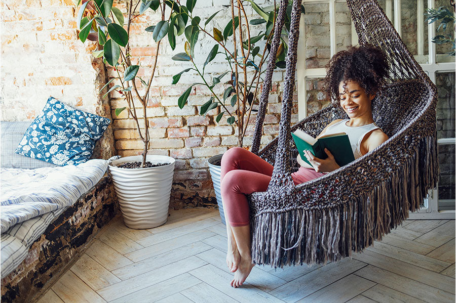 A woman reading in her hammock chair, nestled in her cozy hammock nook.