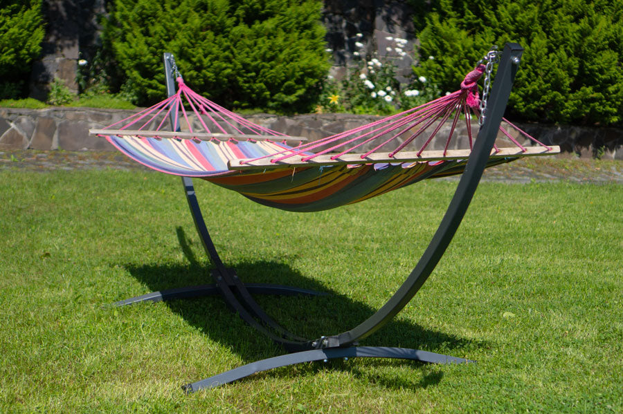 A hammock on a stand in a sunny backyard.