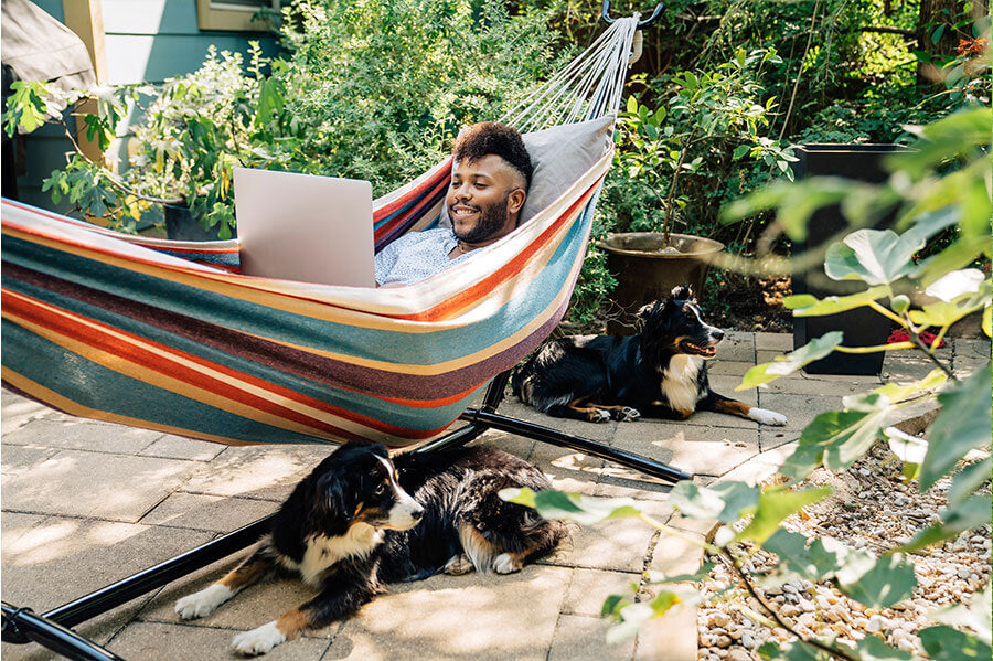 A man relaxing in his eco-friendly hammock outdoors, enjoying quality time with his dogs.