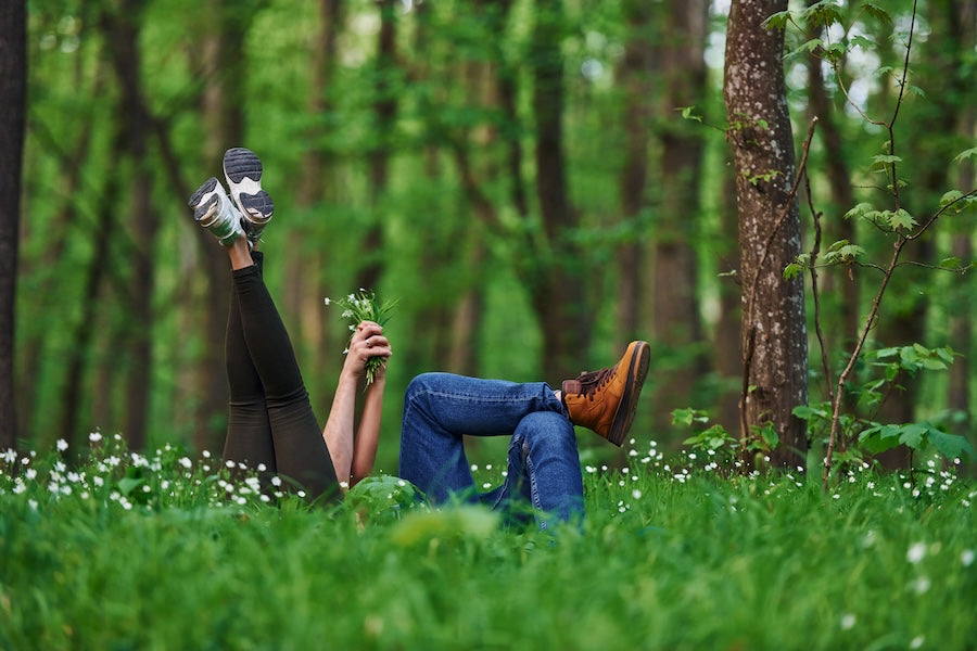 two people on the grass with their feet in the air, forrest setting